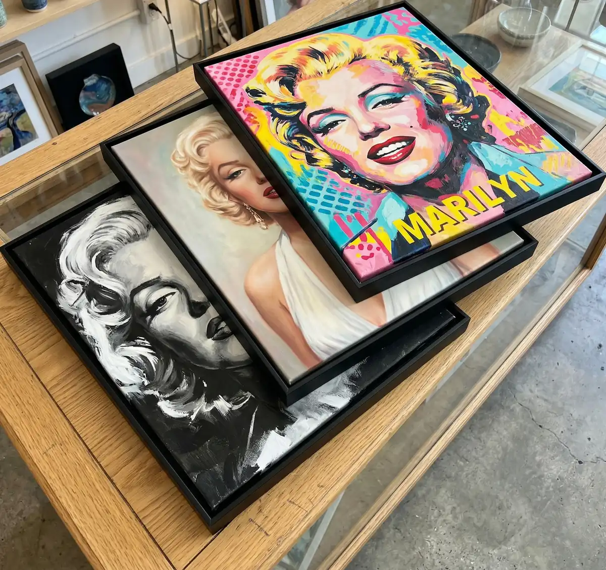 Três estilos diferentes do quadro Marilyn Monroe sobre uma bancada de uma loja de quadros decorativos